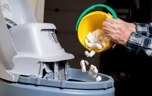 person adds salt to water softener