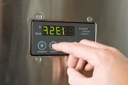 man finger turning down tankless water heater temperature